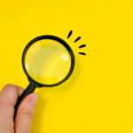 虫眼鏡を持つ女性の手元