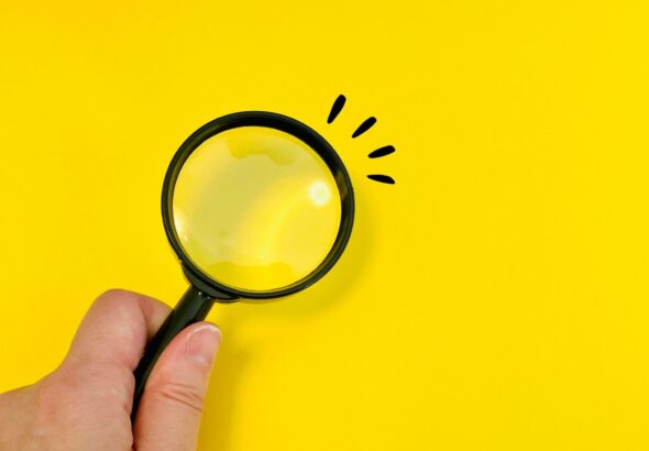 虫眼鏡を持つ女性の手元