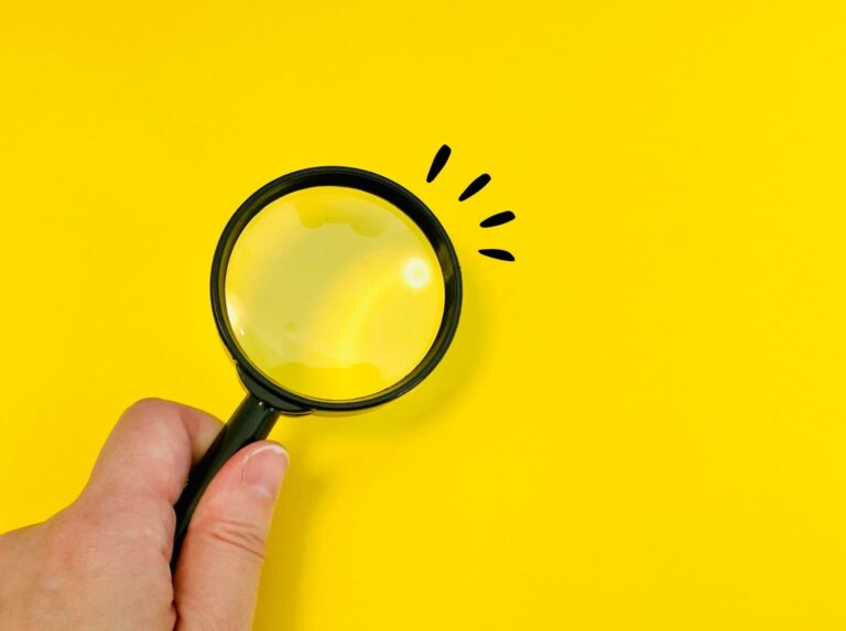 虫眼鏡を持つ女性の手元